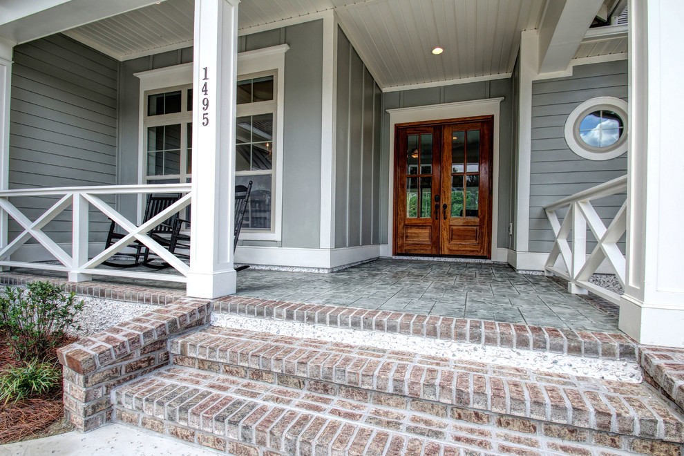This is an example of a large coastal stamped concrete front porch design in Wilmington.