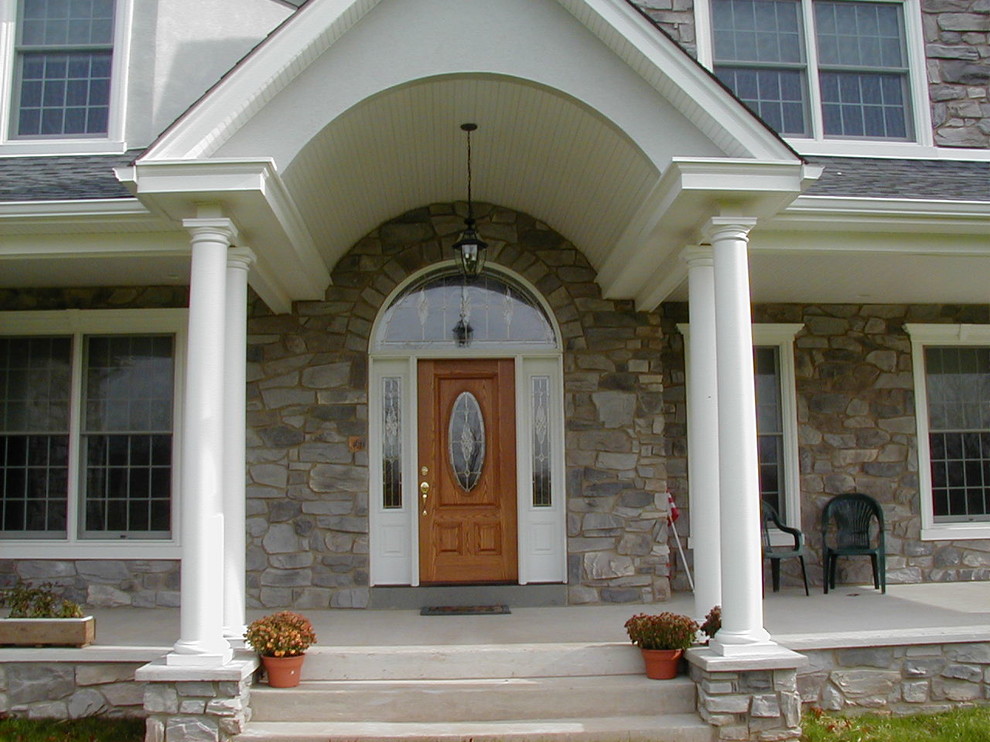 This is an example of a large traditional concrete front porch design in Philadelphia with a roof extension.