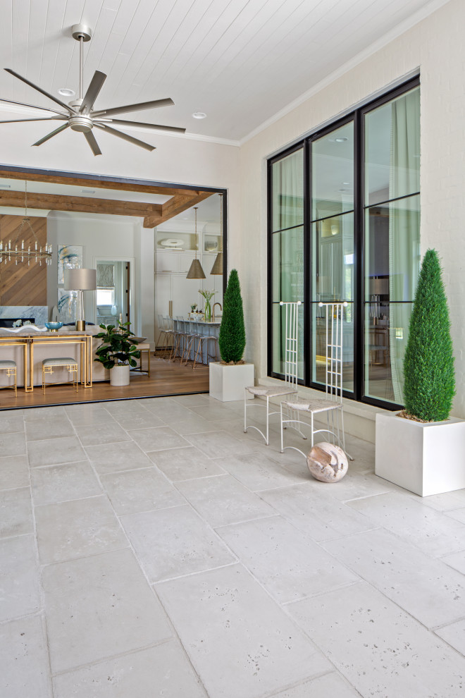 Cette image montre un porche d'entrée de maison design avec des pavés en béton et une extension de toiture.