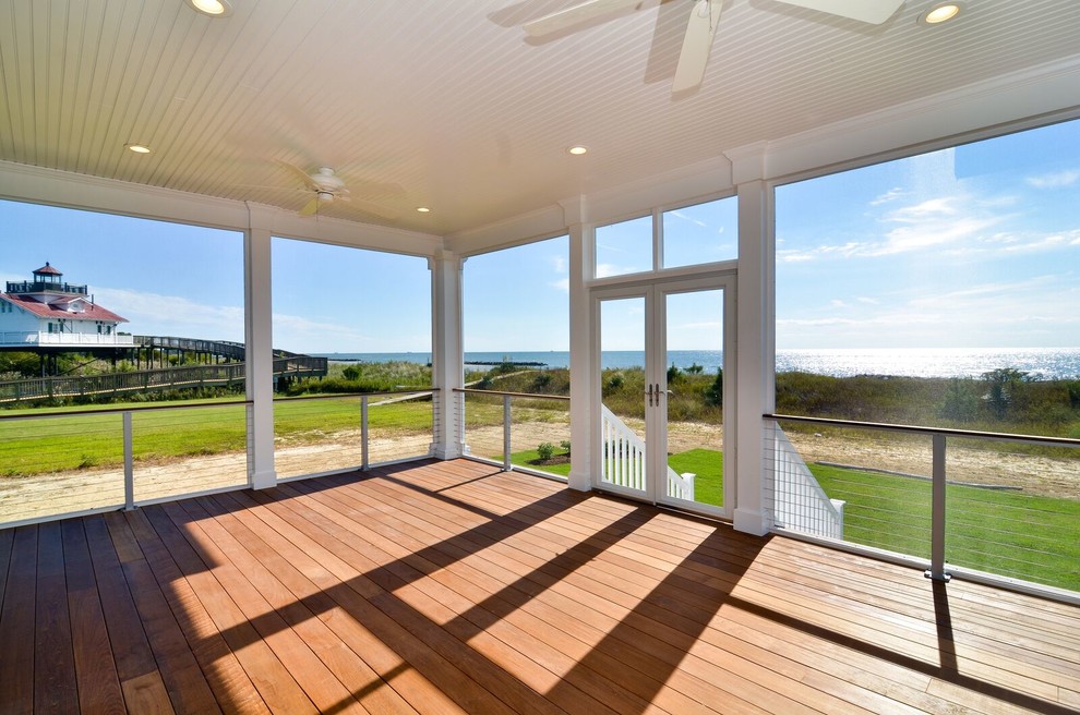 Cette image montre un grand porche d'entrée de maison avant marin avec une moustiquaire, une terrasse en bois et une extension de toiture.