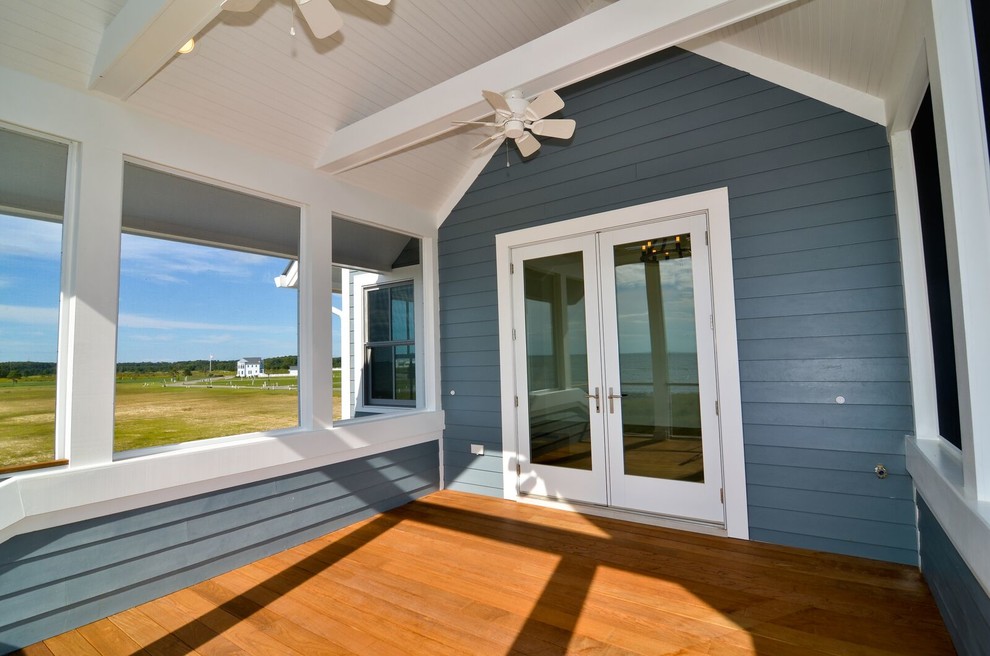 Idées déco pour un grand porche d'entrée de maison avant bord de mer avec une terrasse en bois, une extension de toiture et une moustiquaire.
