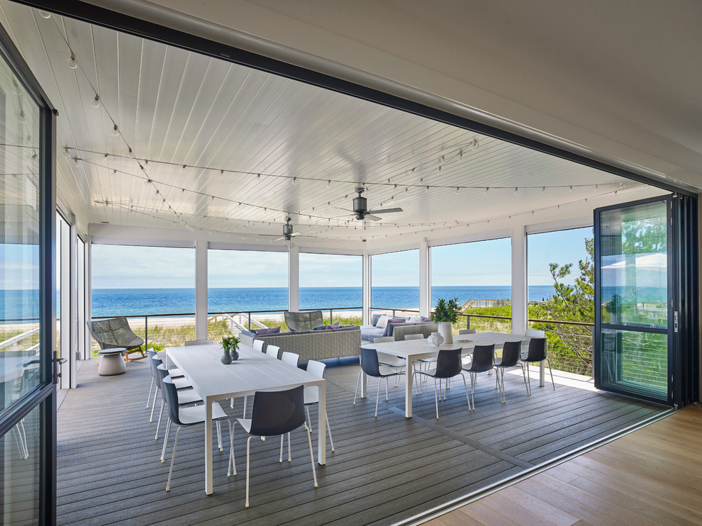 Inspiration for a large contemporary back screened veranda in Other with decking and a roof extension.