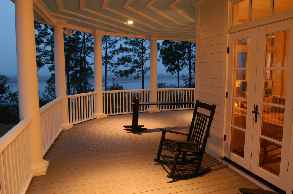 Expansive traditional front screened wood railing veranda in Charleston with a roof extension.