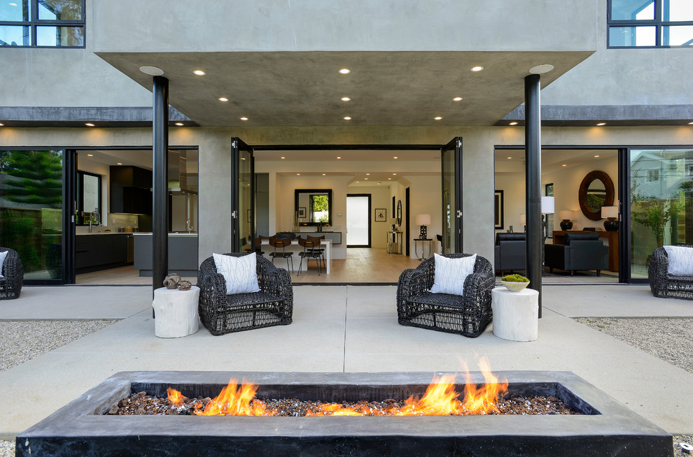 Design ideas for a modern back patio in Los Angeles with a fire feature, concrete slabs and a roof extension.