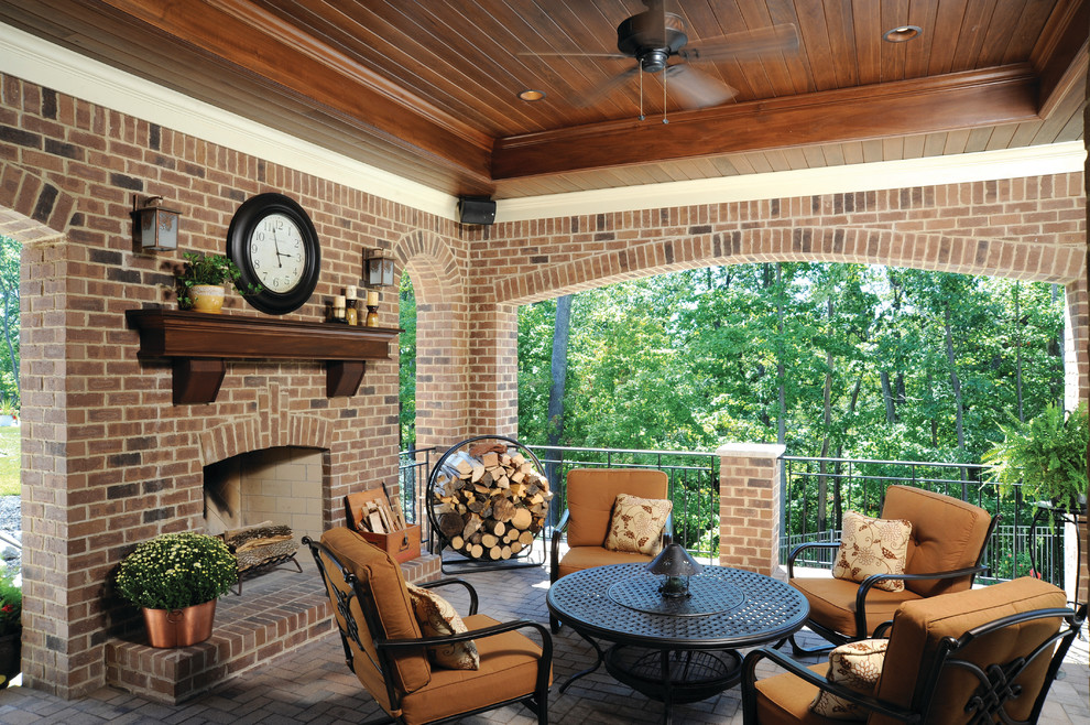 This is an example of a large traditional brick back porch design in Cincinnati with a fire pit and a roof extension.