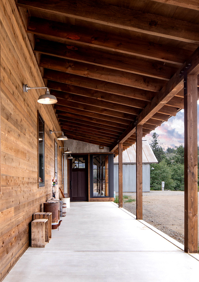 Cette image montre un porche d'entrée de maison avant chalet de taille moyenne avec une dalle de béton et une extension de toiture.