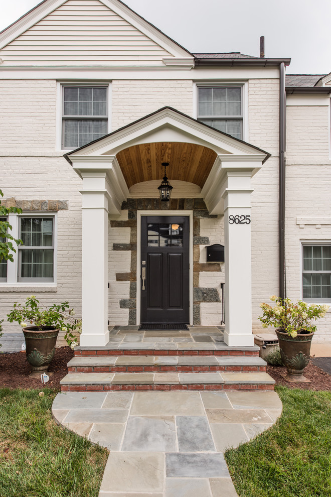 Mid-sized eclectic stone front porch idea in DC Metro with a roof extension