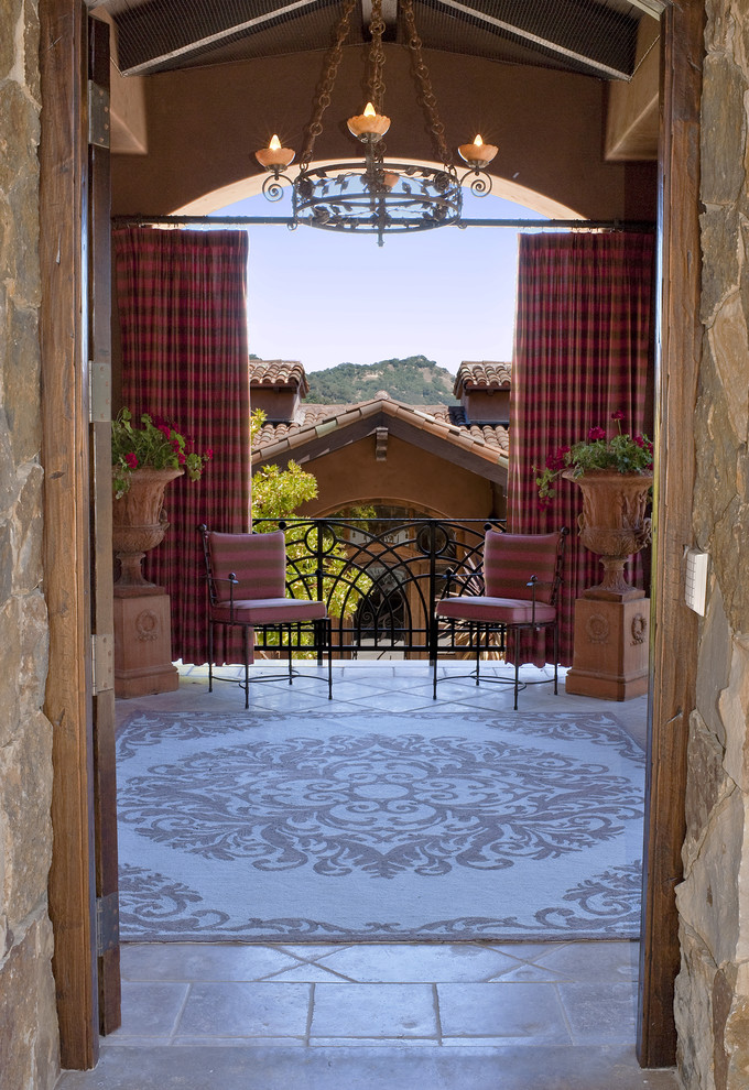 На фото: большая веранда на заднем дворе в средиземноморском стиле с покрытием из каменной брусчатки и навесом