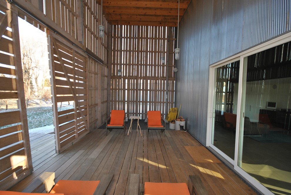 Exempel på en industriell veranda, med trädäck och takförlängning