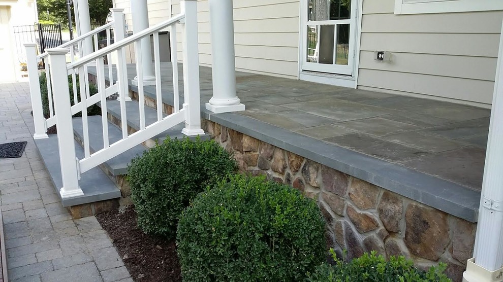 Mid-sized classic stone front porch idea in New York with a roof extension