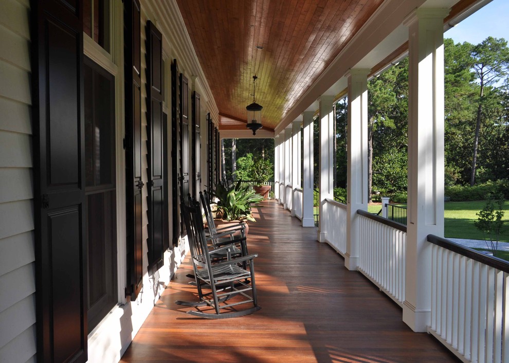 Cette image montre un grand porche d'entrée de maison traditionnel avec une terrasse en bois et une extension de toiture.