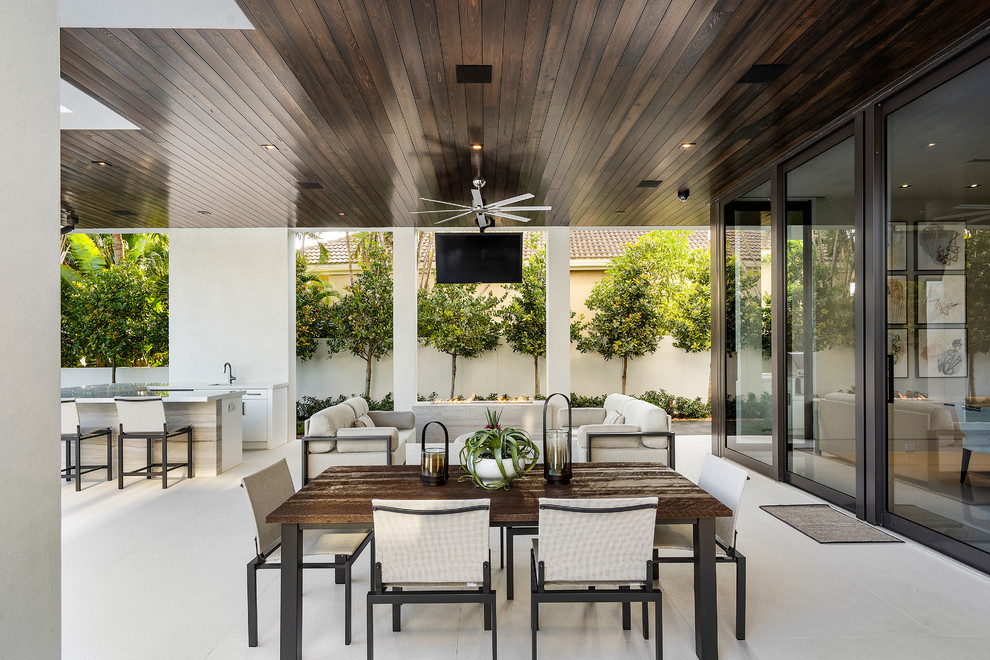 This is an example of a large modern tile back porch design in Miami with a fireplace and a roof extension.