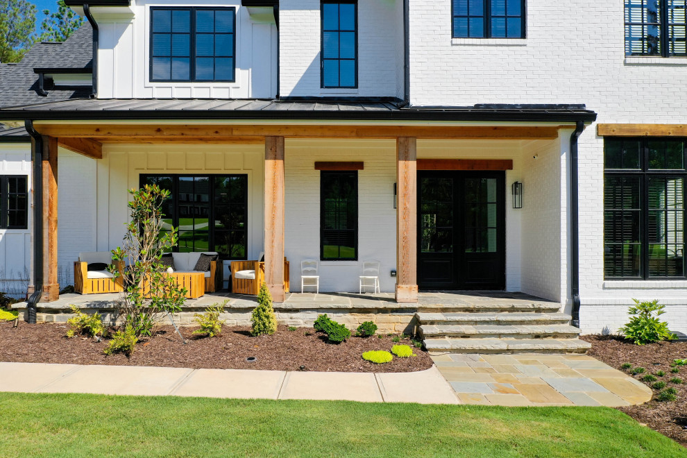 Aménagement d'un grand porche d'entrée de maison avant campagne avec des pavés en pierre naturelle et une extension de toiture.