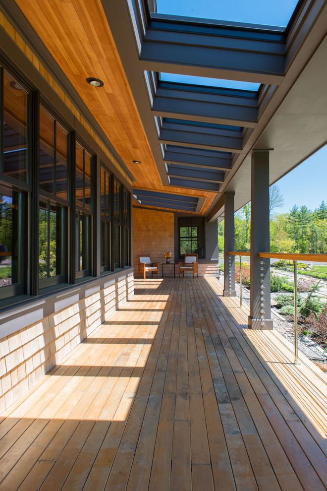 Cette photo montre un grand porche d'entrée de maison latéral craftsman avec une terrasse en bois et une extension de toiture.