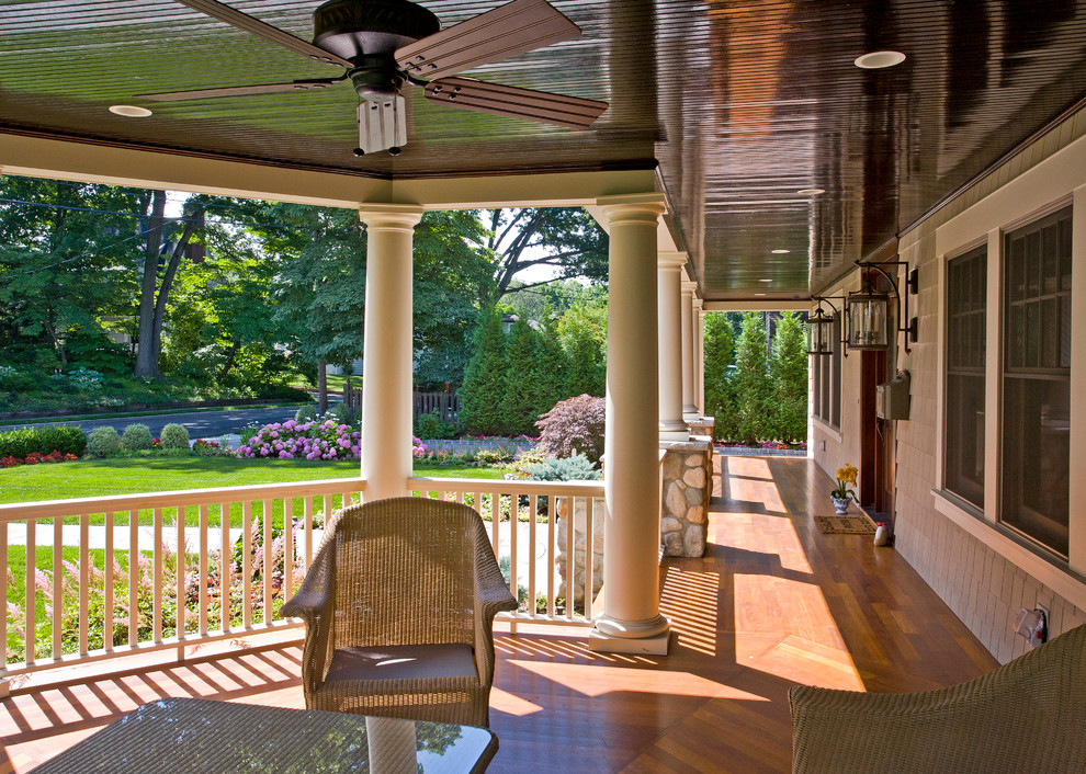 This is an example of a large traditional front veranda in New York with decking and a roof extension.