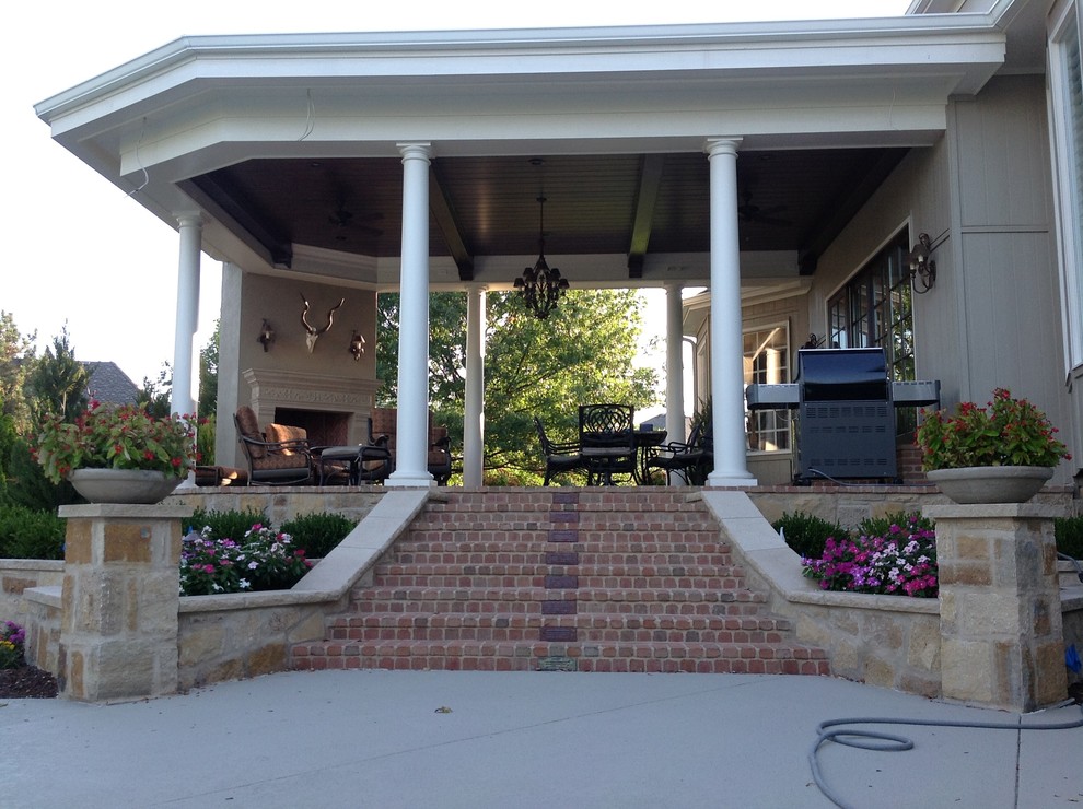 Large elegant brick back porch photo in Kansas City with a fire pit and a roof extension
