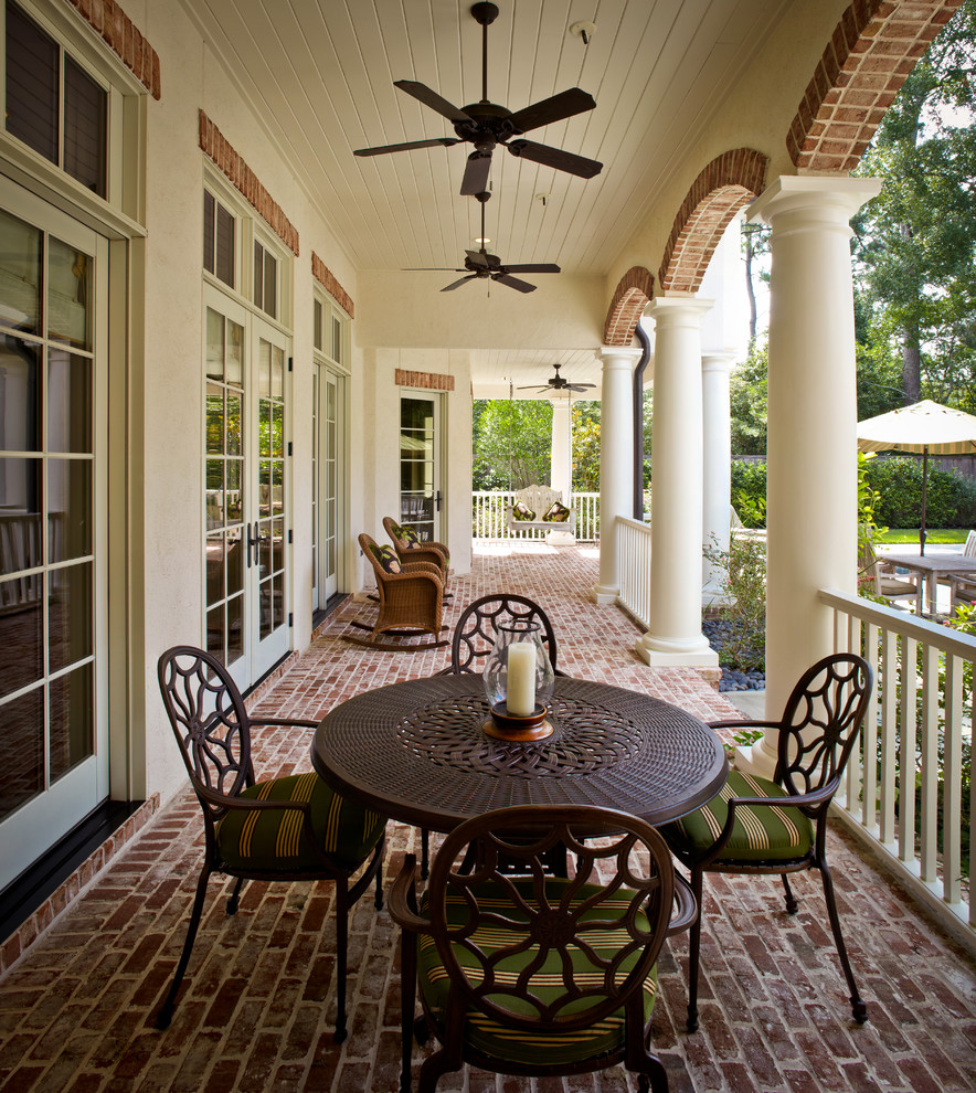 Mid-sized elegant brick back porch photo in Houston with a roof extension