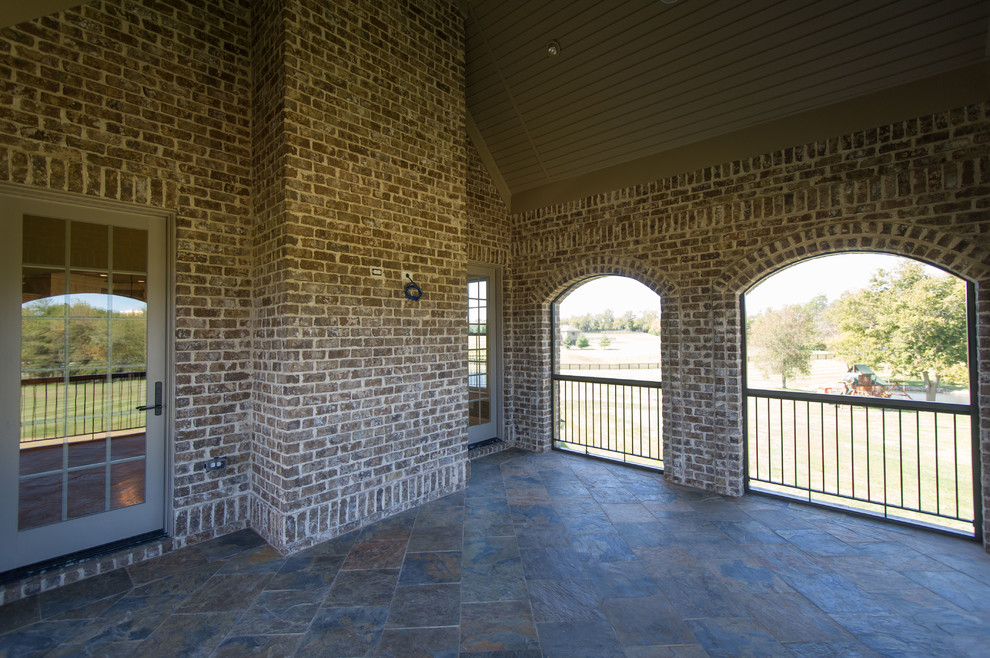 Cette image montre un très grand porche d'entrée de maison arrière traditionnel avec des pavés en pierre naturelle.