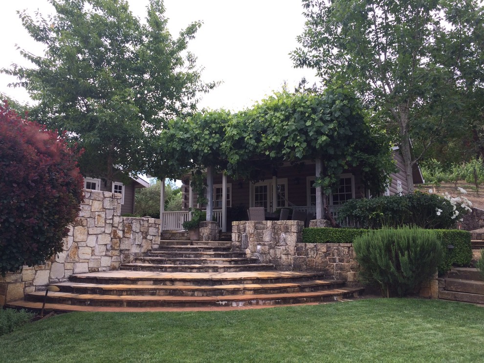 Cette photo montre un porche d'entrée de maison arrière tendance de taille moyenne avec des pavés en pierre naturelle et une pergola.