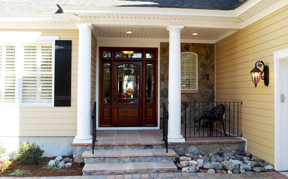 Mid-sized transitional stone front porch photo in Other with a roof extension