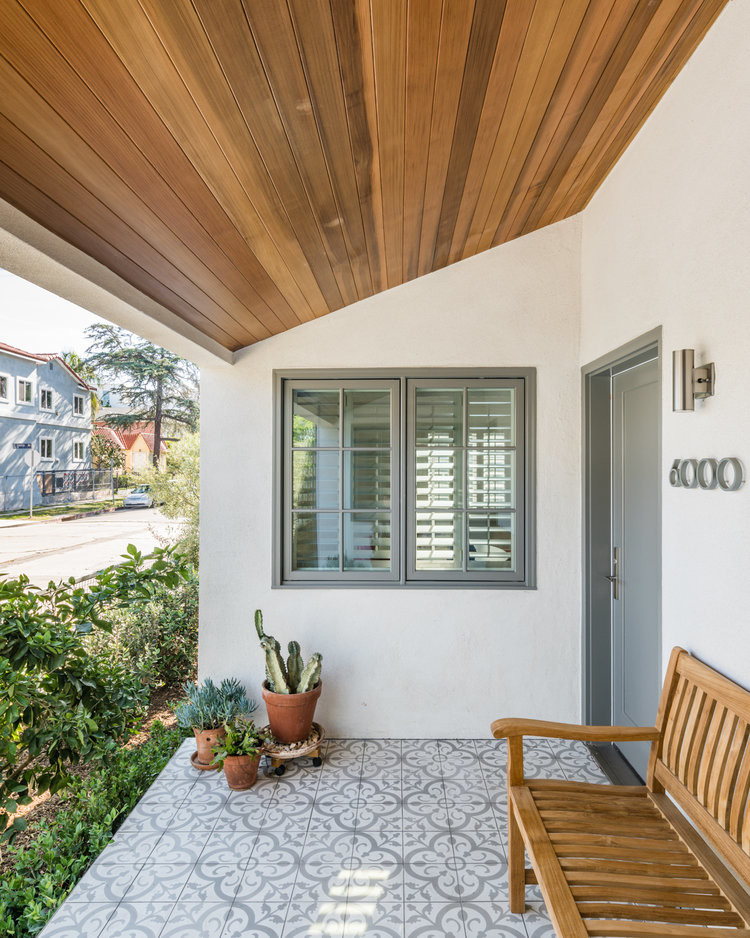 Foto på en liten funkis veranda framför huset, med kakelplattor och takförlängning
