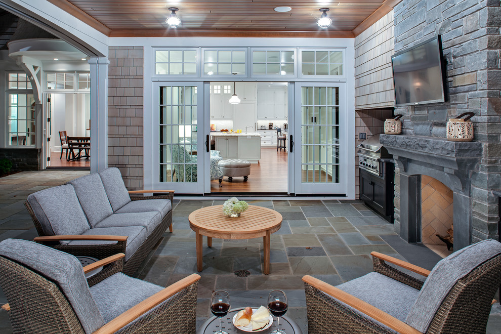 Aménagement d'un porche d'entrée de maison arrière classique avec des pavés en pierre naturelle, une extension de toiture et un foyer extérieur.
