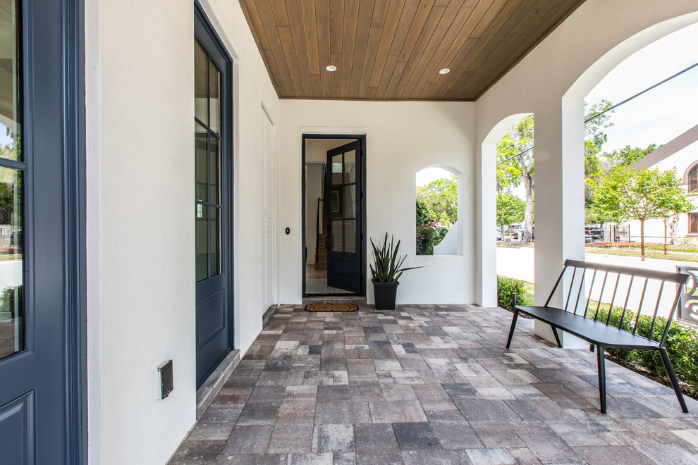 Inspiration for a mid-sized tropical brick porch remodel in Orlando with a roof extension