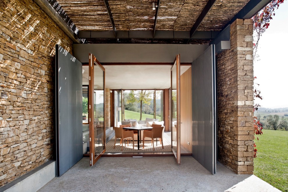 Réalisation d'un porche d'entrée de maison latéral design de taille moyenne avec une dalle de béton et une pergola.