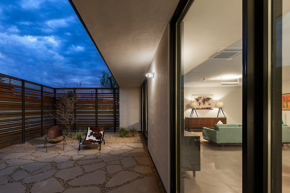 Réalisation d'un porche d'entrée de maison avant minimaliste de taille moyenne avec des pavés en béton et une extension de toiture.