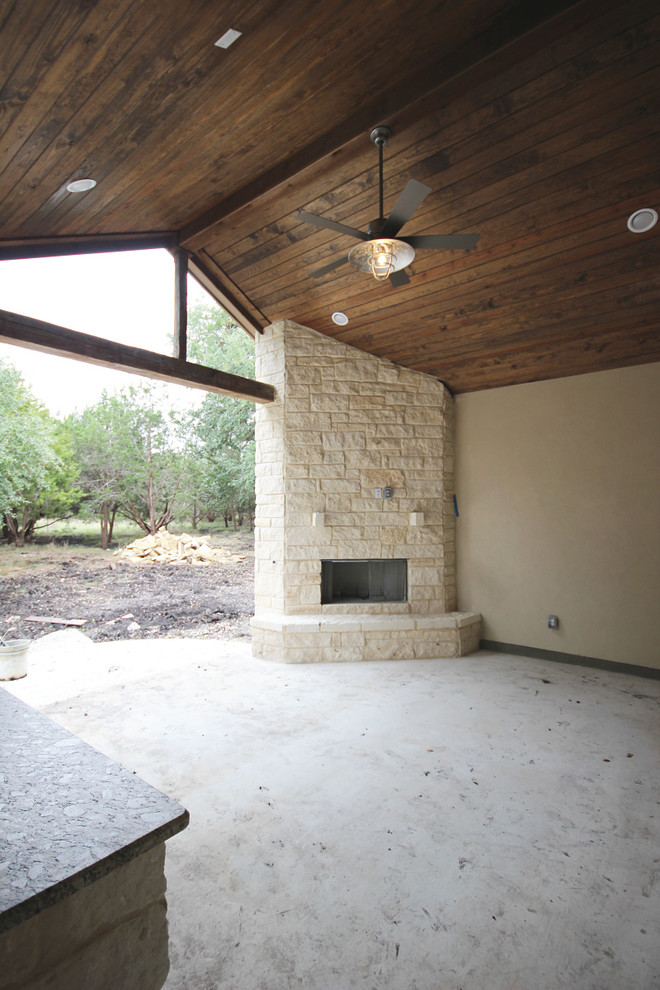 Überdachte Urige Veranda hinter dem Haus mit Kamin und Betonplatten in Austin