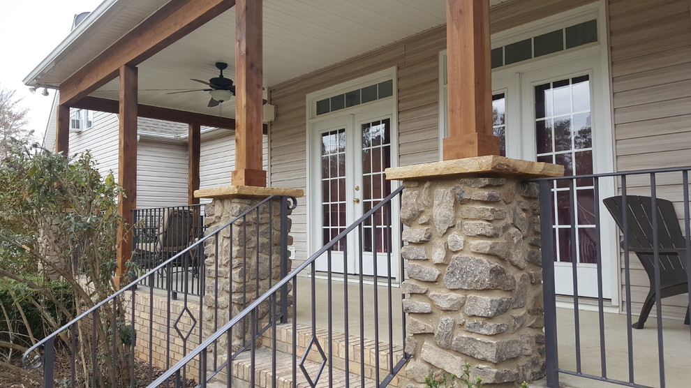Cette photo montre un grand porche d'entrée de maison avant craftsman avec une dalle de béton et une extension de toiture.