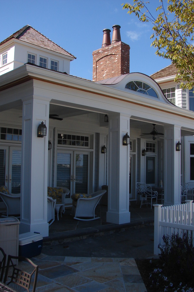 Cette image montre un grand porche d'entrée de maison arrière marin avec des pavés en pierre naturelle et une extension de toiture.