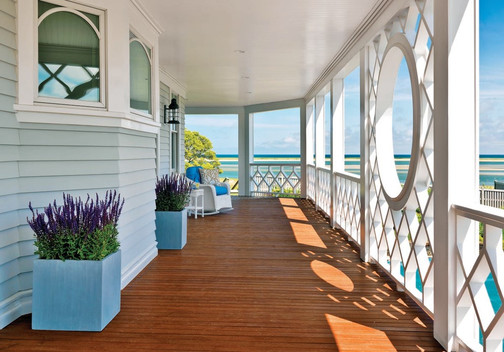 Aménagement d'un grand porche d'entrée de maison avant bord de mer avec une terrasse en bois et une extension de toiture.