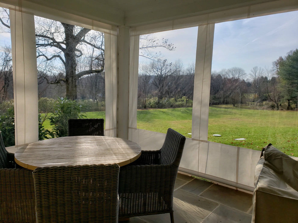 Photo of a large rural back screened veranda in Philadelphia with an awning.