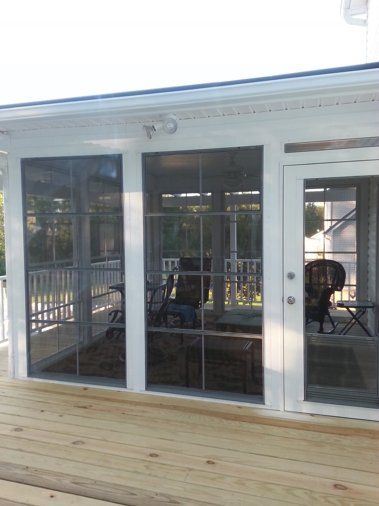 This is an example of a traditional screened-in back porch design in Other with a pergola.