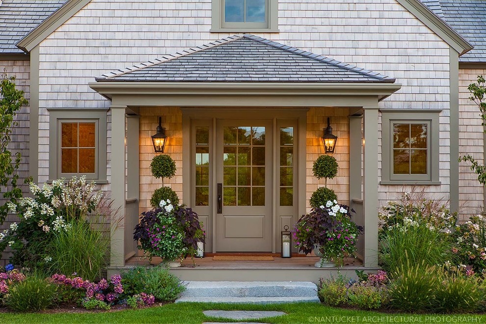 Cette image montre un grand porche d'entrée de maison avant traditionnel avec une terrasse en bois et une extension de toiture.