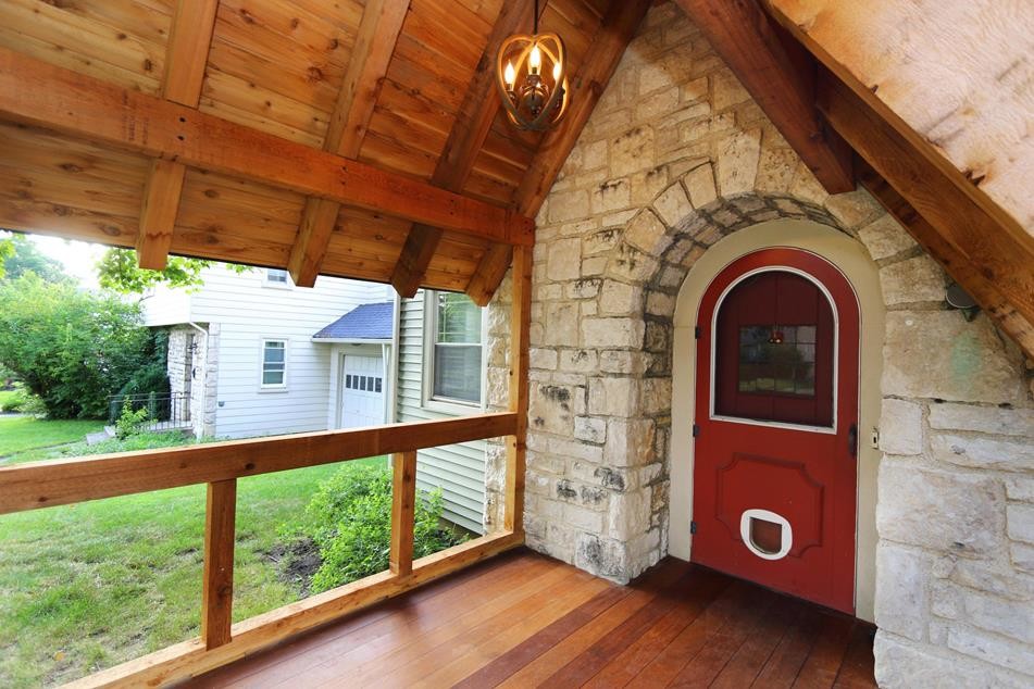 Aménagement d'un petit porche d'entrée de maison avant éclectique avec une terrasse en bois et une extension de toiture.