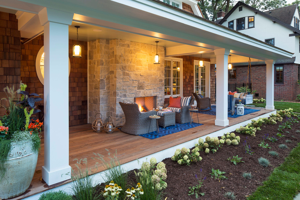 Photo of a large beach style front veranda in Minneapolis with a fire feature and a roof extension.