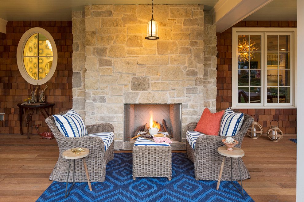 Large beach style front porch photo in Minneapolis with a fire pit and a roof extension