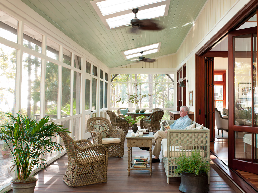 Aménagement d'un grand porche d'entrée de maison arrière classique avec une moustiquaire, une extension de toiture et une terrasse en bois.
