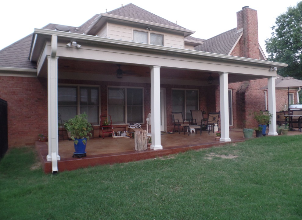 Cette photo montre un grand porche d'entrée de maison arrière chic avec du béton estampé et une extension de toiture.