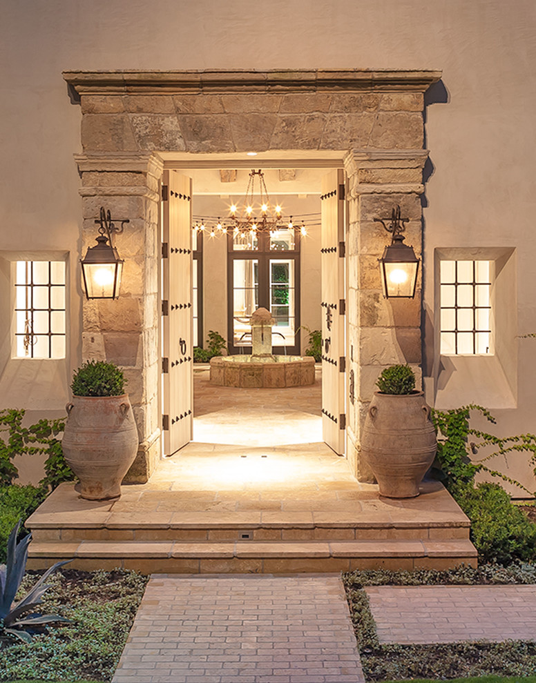 Expansive rustic front veranda in Houston with natural stone paving and feature lighting.