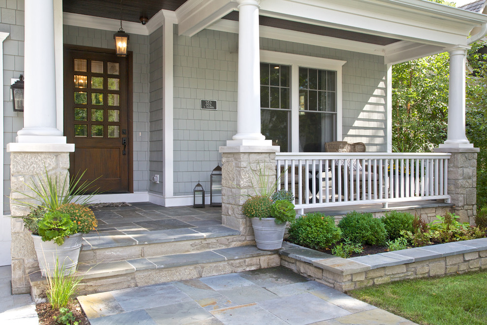 Exemple d'un grand porche d'entrée de maison avant bord de mer avec des pavés en pierre naturelle et une extension de toiture.