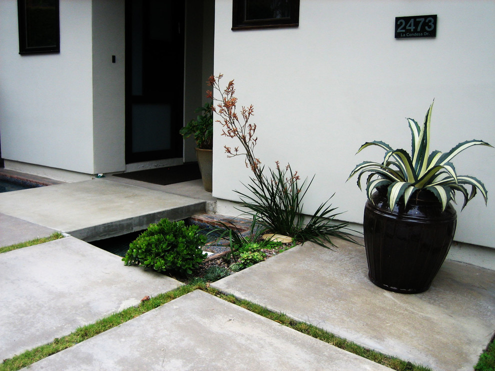 This is an example of a mid-sized modern concrete paver porch design in Los Angeles with a roof extension.
