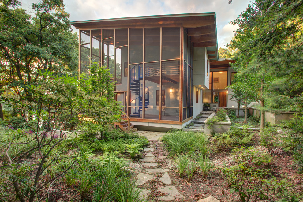 Exemple d'un grand porche d'entrée de maison arrière tendance avec une moustiquaire, une terrasse en bois et une extension de toiture.