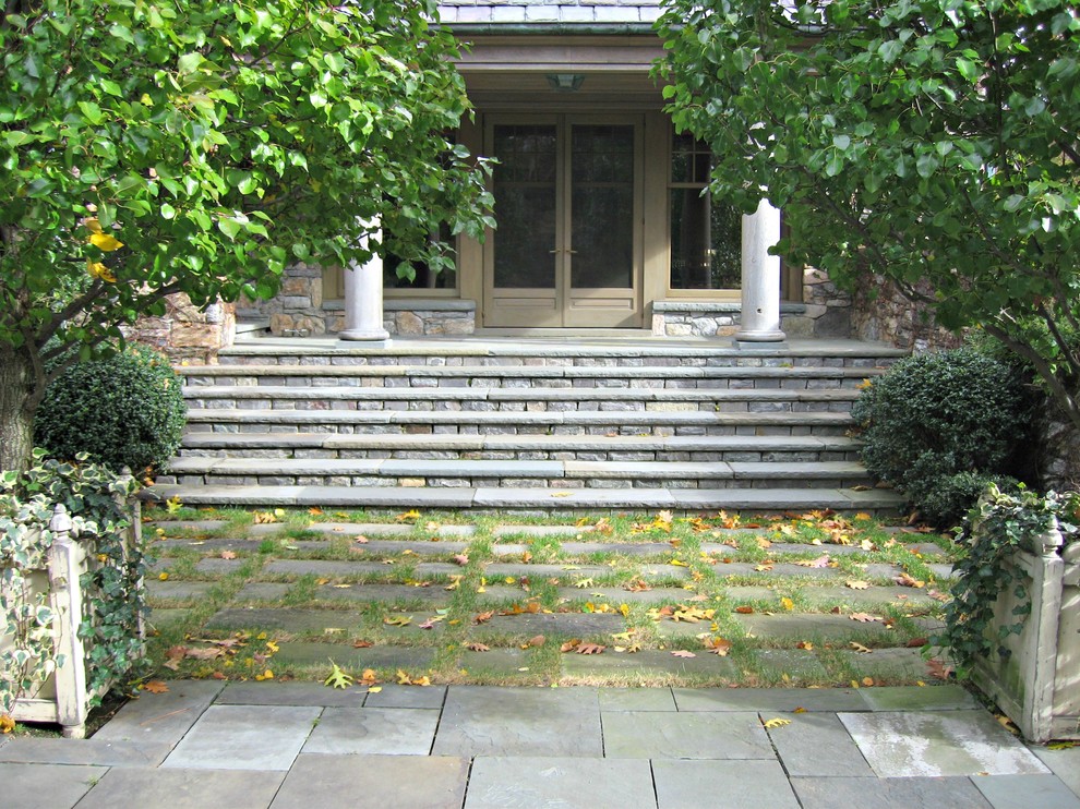Réalisation d'un très grand porche d'entrée de maison avant champêtre avec des pavés en pierre naturelle.