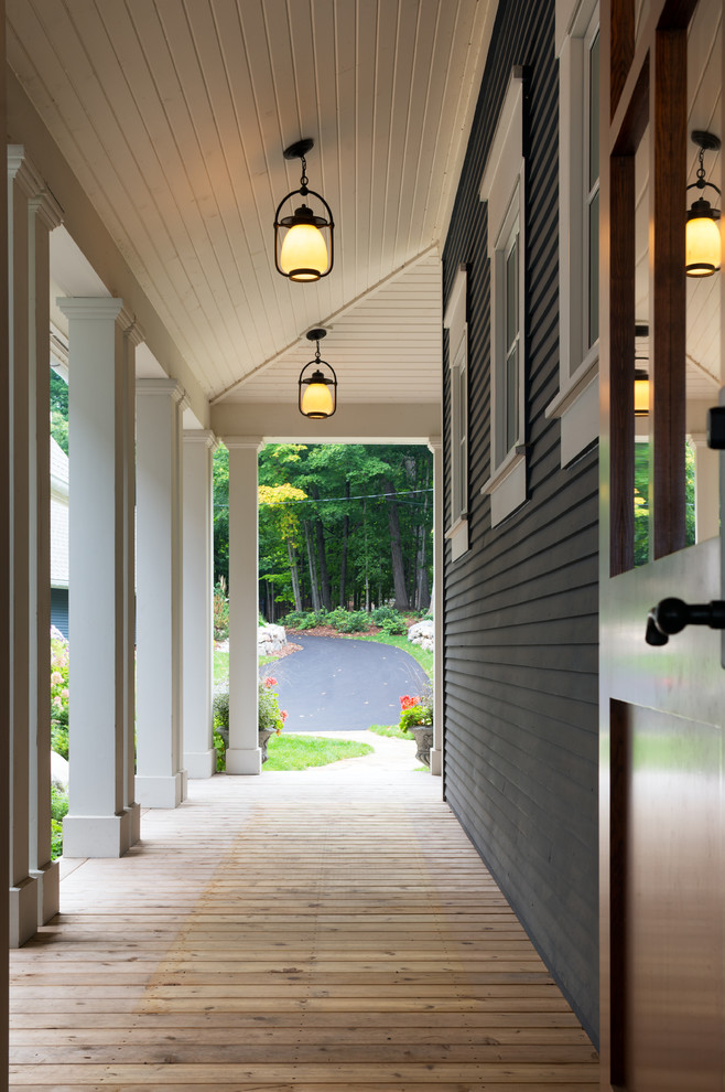 Aménagement d'un grand porche d'entrée de maison avant classique avec une terrasse en bois et une extension de toiture.