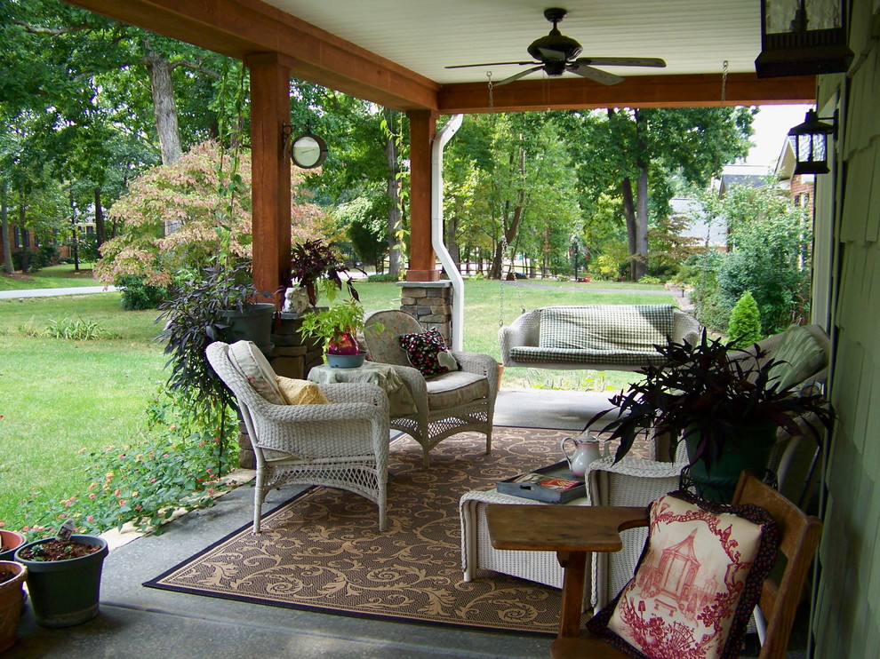 Cette photo montre un porche d'entrée de maison chic avec une dalle de béton et une extension de toiture.