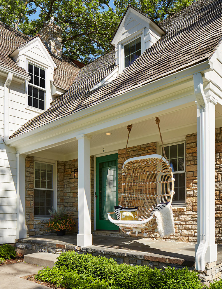 Mid-sized classic stone front porch idea in Minneapolis with a roof extension