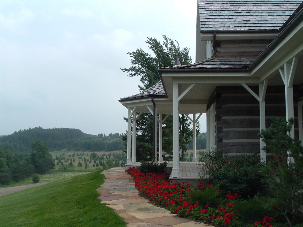 Exemple d'un très grand porche d'entrée de maison avant nature avec une extension de toiture et une terrasse en bois.